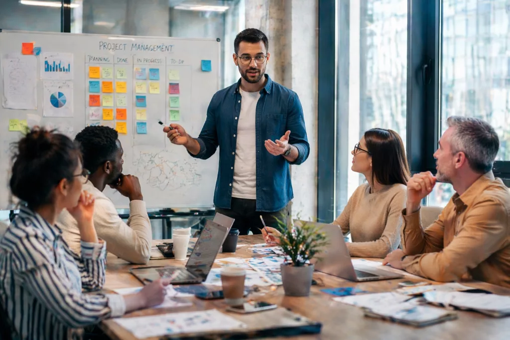 chef de projet en réunion avec son équipe autour d'un tableau de plannification